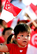 A girl waves the national flag during Singapore's National Day parade at the Padang in Singapore on Tuesday