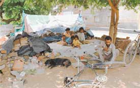 Dhuni Parsad repairs a cycle at his demolished house in Model Town Extension