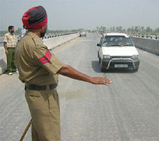 A policemen signals a car to stop as the bridge has been sealed following the SAD decision to inaugurate it on August 13.