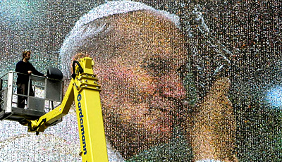 A worker looks at a huge portrait of late Pope John Paul II in Cologne, Germany, on Thursday