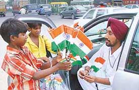 Children sell plastic replicas of the National Flag in Chandigarh on Friday