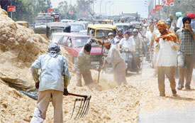 Workers try to clear chaff that blocked traffic on one lane of the Dholewal flyover near Cheema chowk
