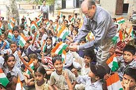 A member of the Bharat Vikas Parishad, Chandigarh , distributes National Flags among students of Government Primary School, Jagat Pura village