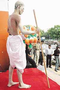A poor man poses as statue of Gandhi outside the office of a telecommunication company in Sector 35, Chandigarh, on the Independence Day eve