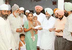 Mr Malkiat Singh Dakha, MLA, and Mr Nahar Singh Gill, Mayor, MC, Ludhiana, present cheques for ex gratia of Rs 1 lakh to the next of the kin of the victims of an accident in Simla Puri