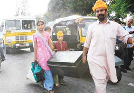 Passengers from a Punjab Roadways bus carry their luggage after it did not proceed beyond the Mohali-Chandigarh barrier due to the ongoing row between the CTU and Punjab Roadways at Phase VI, Mohali, on Monday.
