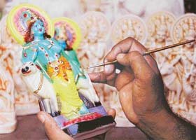 An artist gives finishing touches to an idol of Lord Krishna, ahead of the Janamashtami, at the Triveni Chowk in Patiala