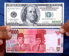 An Indonesian holds a $ 100 note and a 1,00,000 rupiah note in Jakarta on Friday.