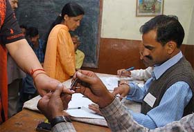 Election officer marks ink on a womans hand at ward no. 4, at Anandale, Shimla