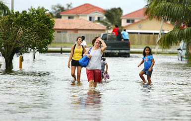 People walk down the street in a flooded neighbourhood in South Miami Dade County, Florida, on Saturday. Hurricane Katrina gathered strength in the Gulf of Mexico for a second and potentially more deadly assault on the US coast after killing seven persons on its trek across southern Florida.