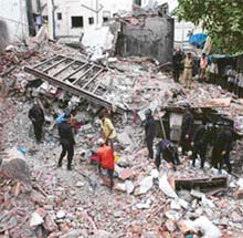 Rescue workers remove debris of a three-storey building which collapsed at Dhobitalao near Metro cinema in Mumbai