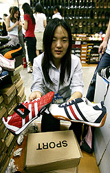 A vendor shows fake Adidas shoes for sale at a market in Beijing on Wednesday