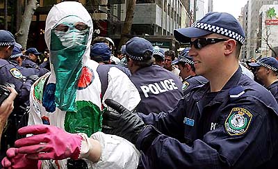 The police arrests a masked protester attempting to reach the Forbes Global CEO Conference being held in the Sydney Opera House on Wednesday