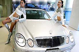 South Korean models pose with a Mercedes-Benzs E280 during a press unveiling in Seoul on Monday