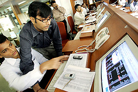 Stock dealers gesture as they monitor their screens during intra-day trading in Mumbai on Monday