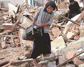 A girl collecting her household items from her demolished house at Kajehri village