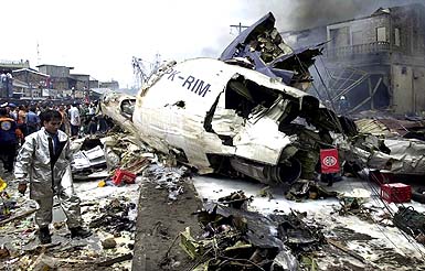 Indonesian search and rescue personnel inspect the wreckage of a Mandala Airlines plane that crashed in Medan, North Sumatra, on Monday