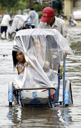 A Cambodian cyclo driver makes his way across a flooded street in Phnom Penh on Wednesday. Heavy rain overburdened the capital's old sewer systems, causing floods.