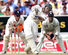 Australias Justin Langer hits a six as Englands Geraint Jones and Marcus Trescothick look on 