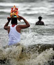 A devotee carries an idol of Lord Ganesh for immersion in the Arabian Sea off the coast of Mumbai on Monday.