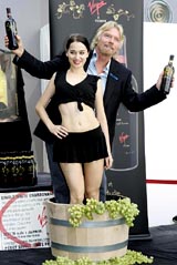 Sir Richard Branson stands in a tub of grapes with a model as he holds bottles of new Virgin Vines, a new line of wine with the Virgin label, launched during the Fashion Week in New York on Monday