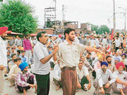 Workers of the Mukerian paper mill block traffic on the national highway near Civil Hospital in Mukerian on Tuesday.
