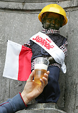 A man fills a glass with draft beer pouring from Brussels' famous Manneken Pis statue