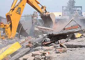 The structure of a marble shop being pulled down during a demolition drive at Raipur Khurd village on Thursday
