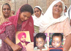 Kuldip Kaur shows a picture of her husband Baljinder Singh and two children at Charik village in Moga on Thursday.