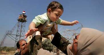 An Egyptian woman helps her baby to cross the Egyptian-Palestinian-controlled border in Rafah, southern Gaza Strip, on Thursday