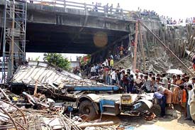 People gather at the scene of an accident where a bus fell off an overbridge on to the railway track near Bally station in Howrah district near Kolkata on Friday.
