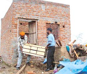 Relatives of Gurnam Singh take things out of his one-room house in Rajpura
