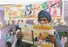 A farmer reads a book on agriculure at the Kisan Mela, PAU, Ludhiana, on Thursday