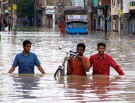 Men wade through water in the Sirki Bazar area of Bathinda after a heavy shower