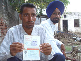 Angrej Singh shows his passport as his brother, Beant Singh, looks on, at Malooka village in Bathinda on Friday.
