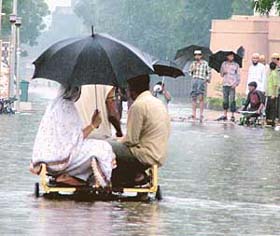 A cycle van carrying passengers wades through water-logged street after a heavy downpour in Ahmedabad