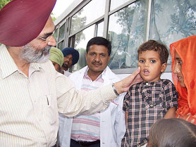 Punjab Health Secretary Darbara Singh Guru examines a child during a medical check-up camp at Lehri village, near Bathinda, on Saturday.