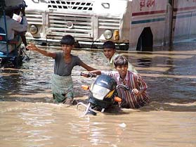 Children push a motor cycle in a waterlogged street after heavy rain in Mathura on Sunday. 