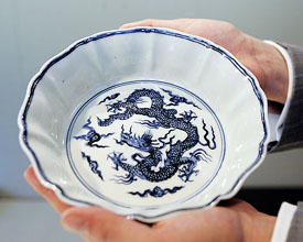 A Sothebys official holds a rare blue and white flower-shaped dragon washer in Hong Kong