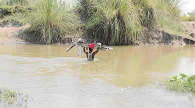 A labourer carries a bicycle as he crosses the Jassowal drain near Kanya Hussaini village