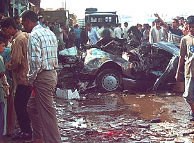 A destroyed vehicle sits near a market after a car bomb exploded in the southern Iraqi town of Hilla, 100 km south of Baghdad, on Friday
