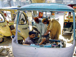 Pakistani mechanics fix a liquefied petroleum gas (LPG) kit on an auto-rickshaw in Karachi on Monday.
