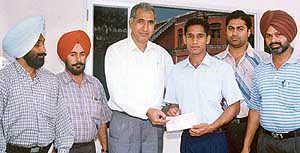 Mr K.K. Sharma, Principal of A.S. Senior Secondary School, Khanna, hands over the scholarship amount to gymnast Kuljinder Singh on Monday. 