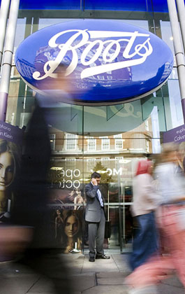 Passersby walk past a Boots Store on Oxford Street in London.