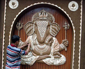 An artist gives finishing touches to an idol of Lord Ganesha, being made of wood waste, at a Durga Puja pandal in South Kolkata on Friday