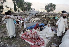 Residents wait for relief under the open sky as their houses were destroyed by a severe earthquake in Balakot, 90 km from Islamabad, on Sunday