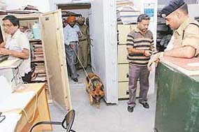Policemen use a sniffer dog to check the premises of Punjab National Bank in Ramgarh village, Kapurthala, where robbers struck on Monday.