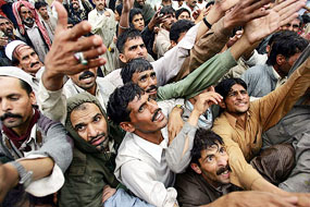 The quake-hit stretch their hands for aid distributed by the government in Muzaffarabad, capital of occupied Kashmir, on Tuesday. 