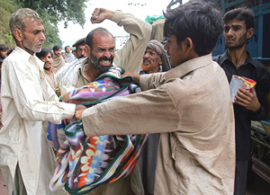 Men fight over a blanket they looted from a local charity truck outside Muzaffarabad, the capital of occupied Kashmir, on Wednesday.