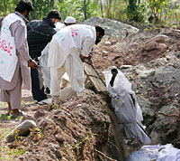 Volunteers lower the body of a victim, wrapped in plastic, into a mass grave in earthquake-devastated Muzaffarabad, capital of Pakistan-occupied Kashmir, on Friday.